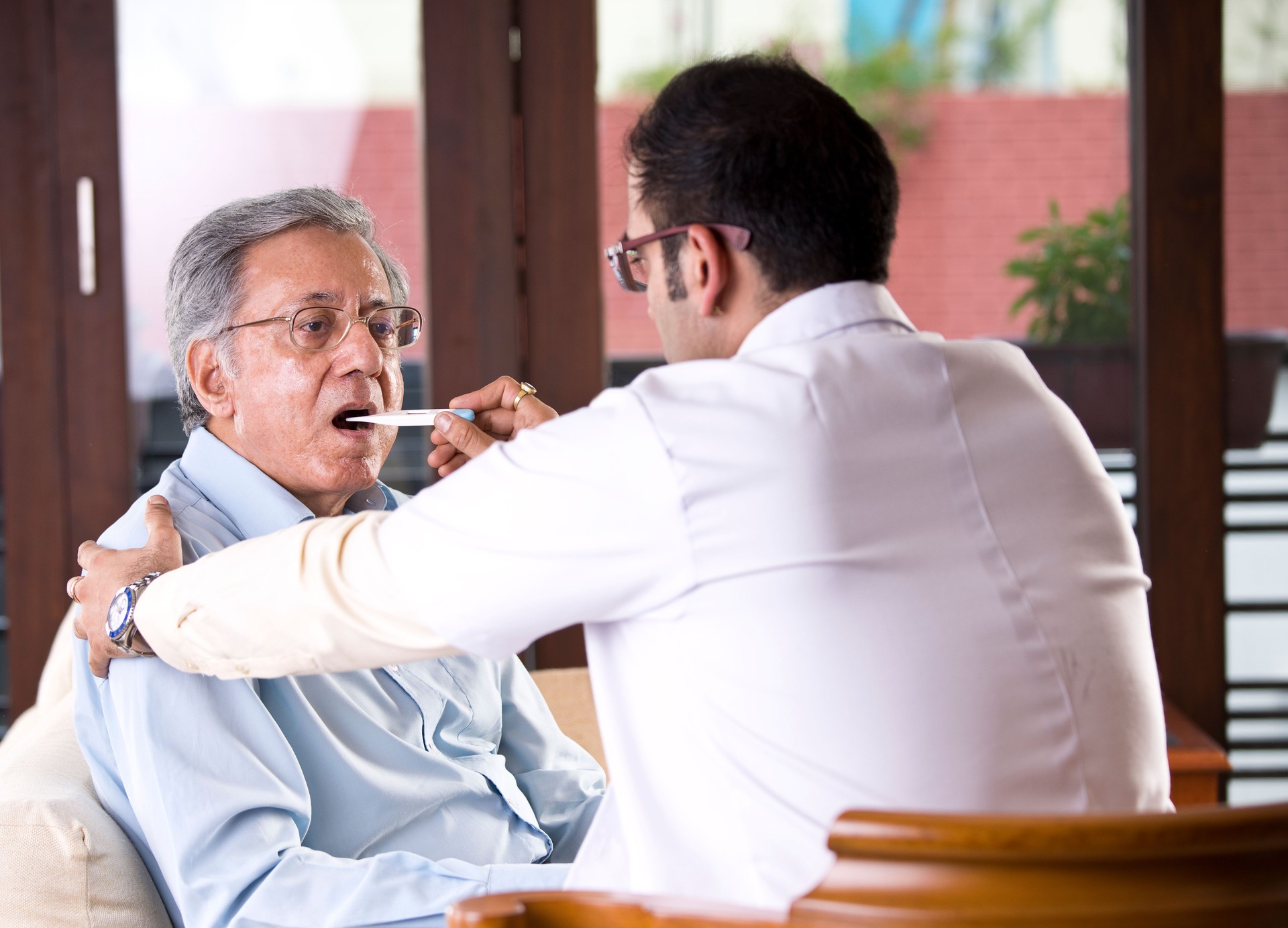 Doctor checking senior man's temperature